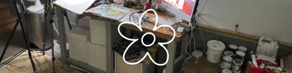 Art table with expressive mixed media flower painting in progress alongside brushes and collage paper